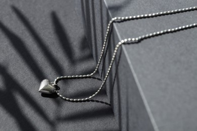 Photo of Metal chain with pendant on black table, closeup. Luxury jewelry