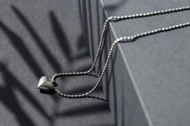 Metal chain with pendant on black table, closeup. Luxury jewelry