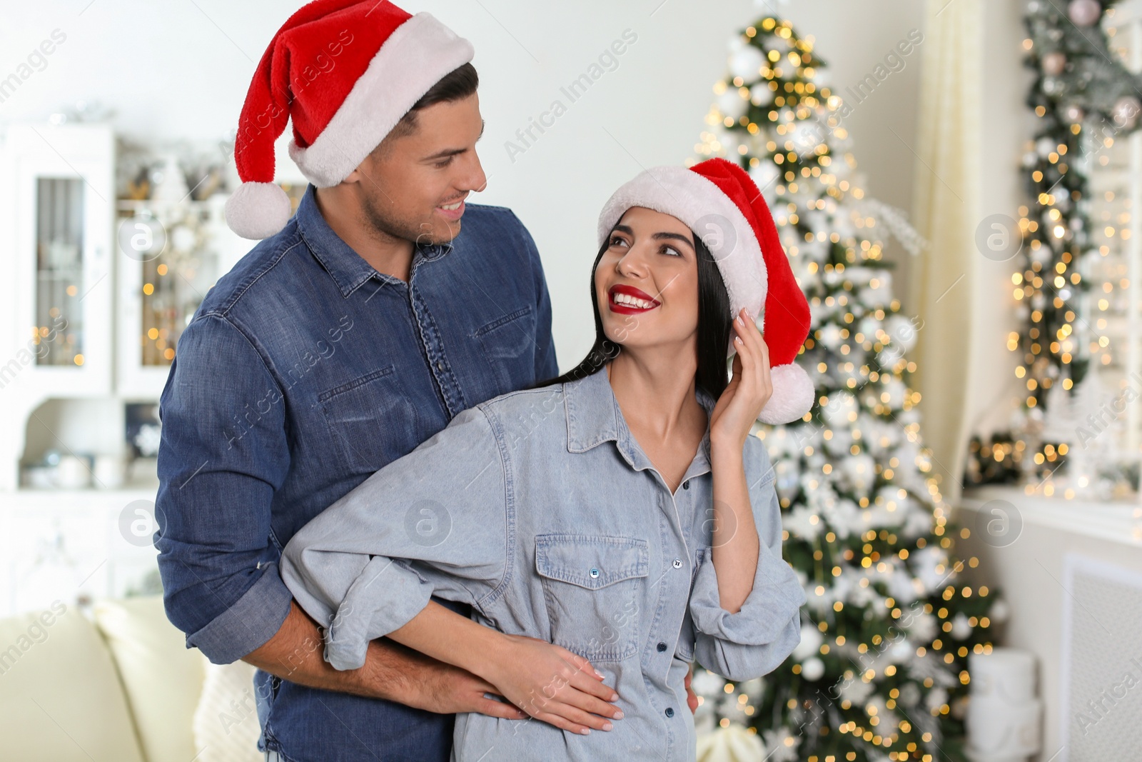 Photo of Happy couple in Santa hats at home. Christmas celebration