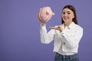 Photo of Sad woman with piggy bank on purple background, space for text