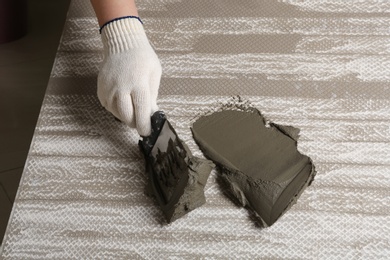 Worker spreading concrete on ceramic tile with spatula, closeup. Space for text