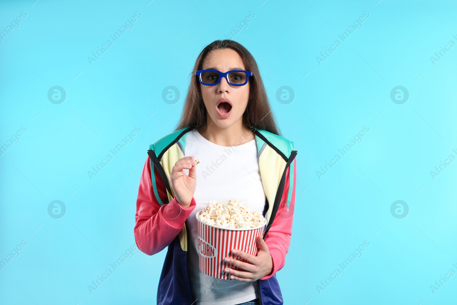 Photo of Emotional woman with 3D glasses and popcorn during cinema show on color background