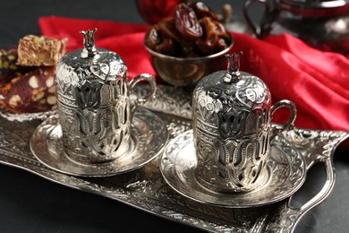 Photo of Tea, Turkish delight and date fruits served in vintage tea set on black table
