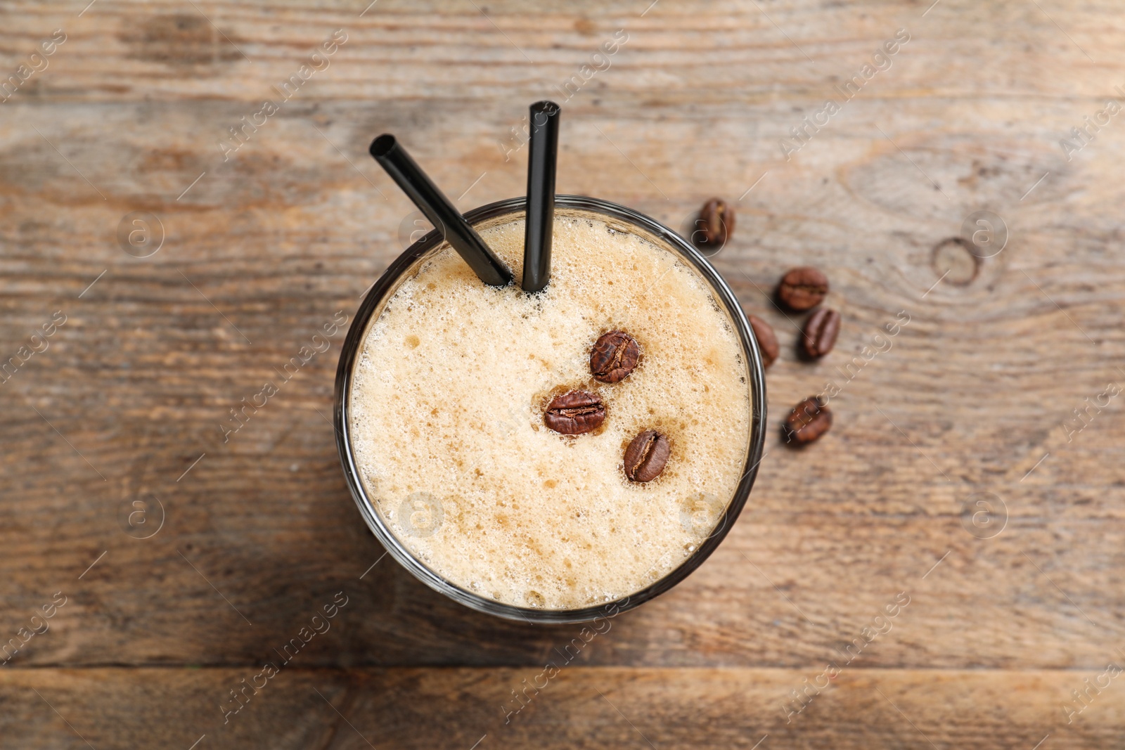 Photo of Glass of tasty refreshing cocktail with coffee beans on wooden background, top view