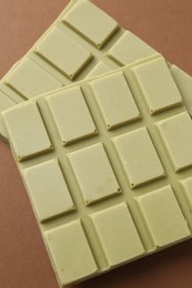 Pieces of tasty matcha chocolate bar on brown background, closeup