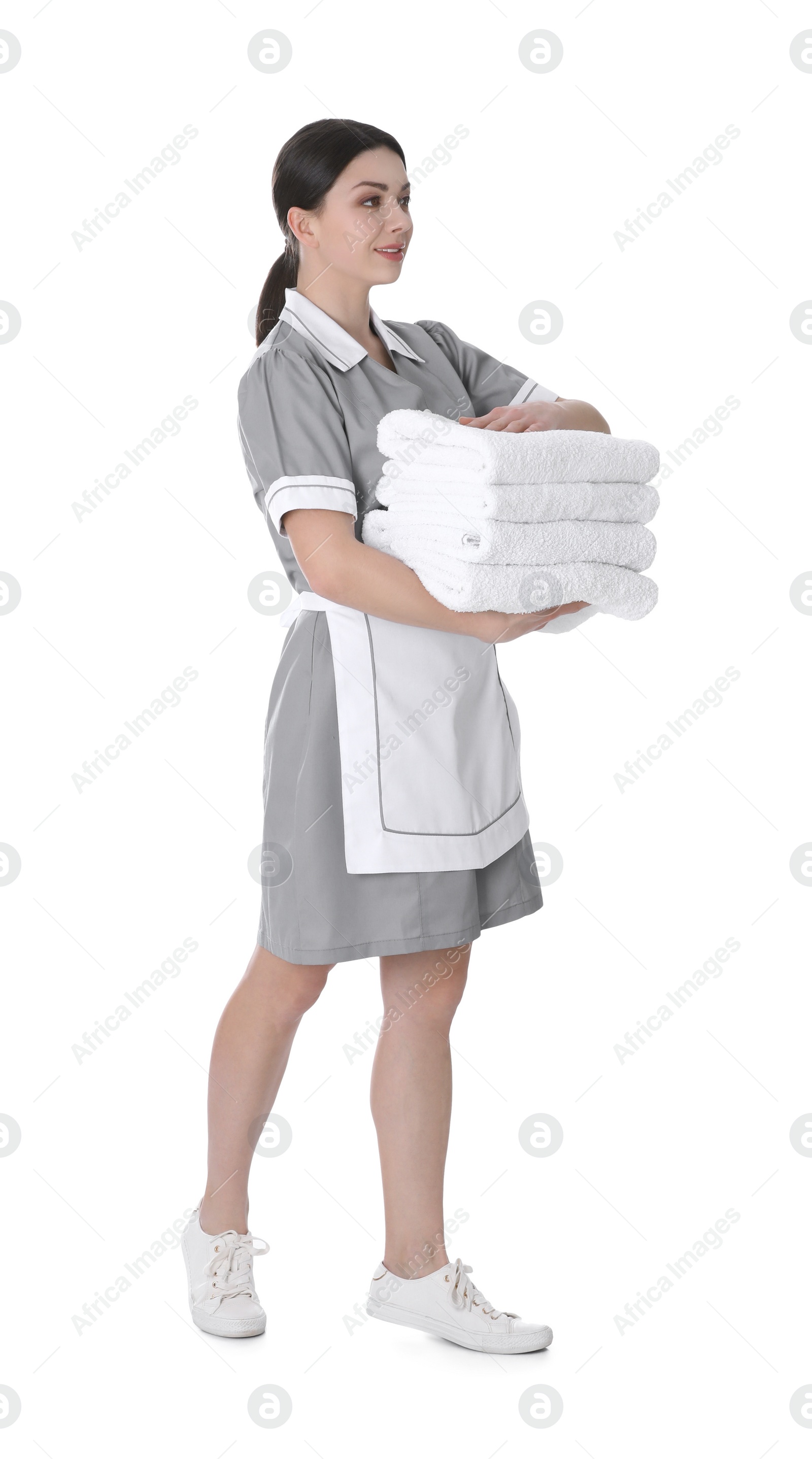 Photo of Young chambermaid holding stack of fresh towels on white background