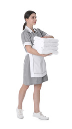 Young chambermaid holding stack of fresh towels on white background