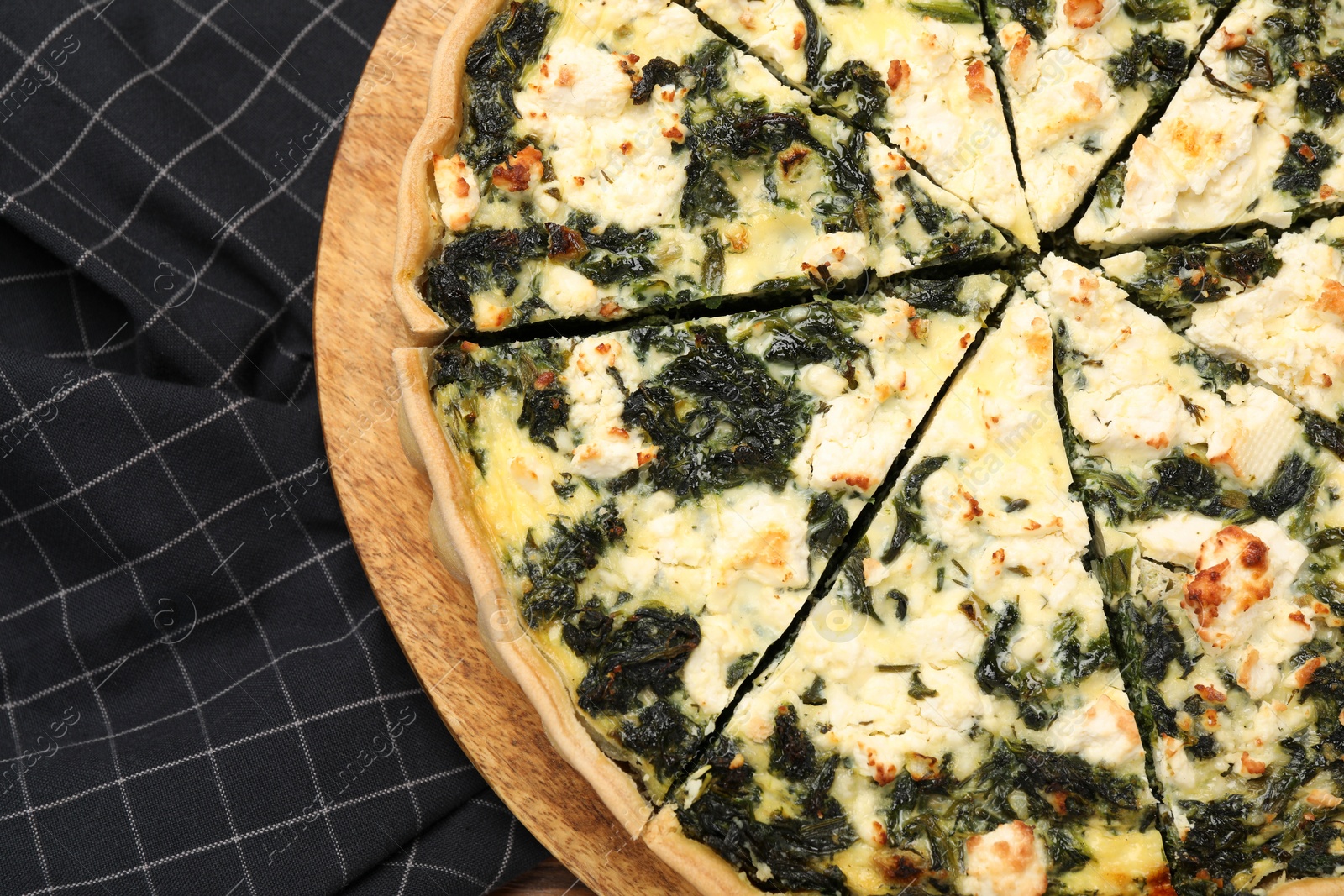 Photo of Delicious homemade spinach quiche on black tablecloth, top view