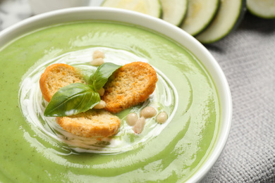 Tasty homemade zucchini cream soup in bowl on table, closeup