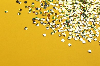 Photo of Shiny bright glitter on yellow background. Space for text