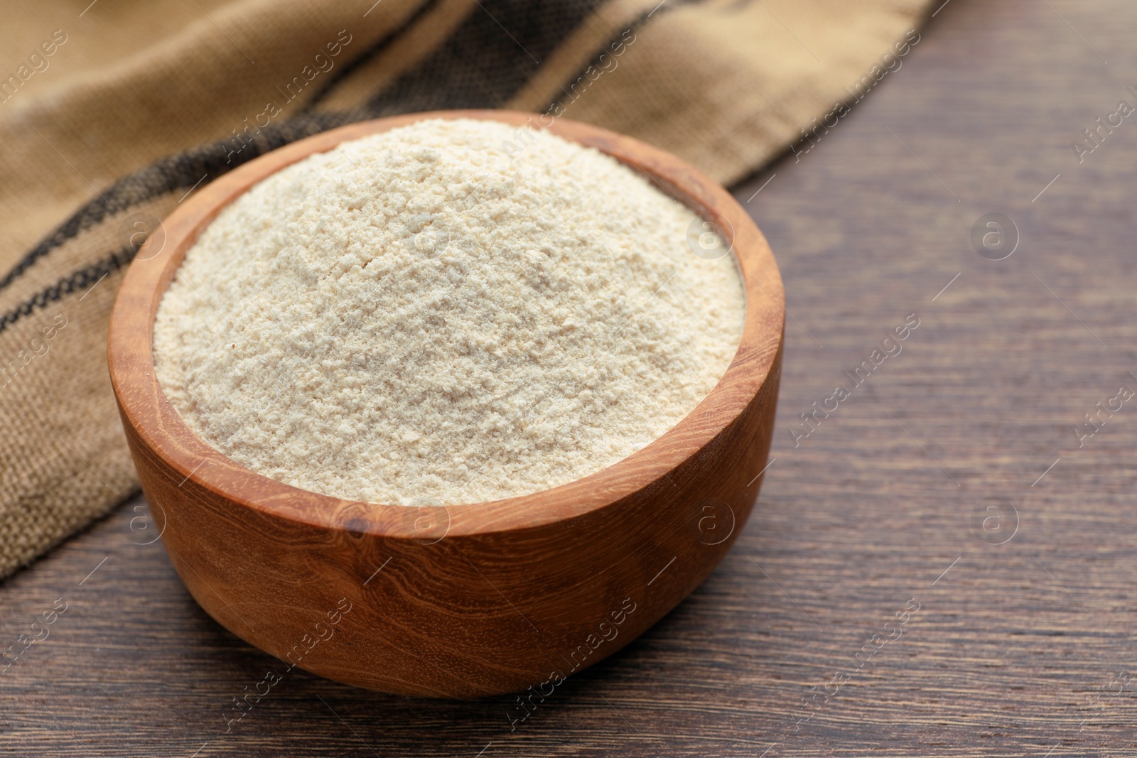 Photo of Quinoa flour in wooden bowl on wooden table