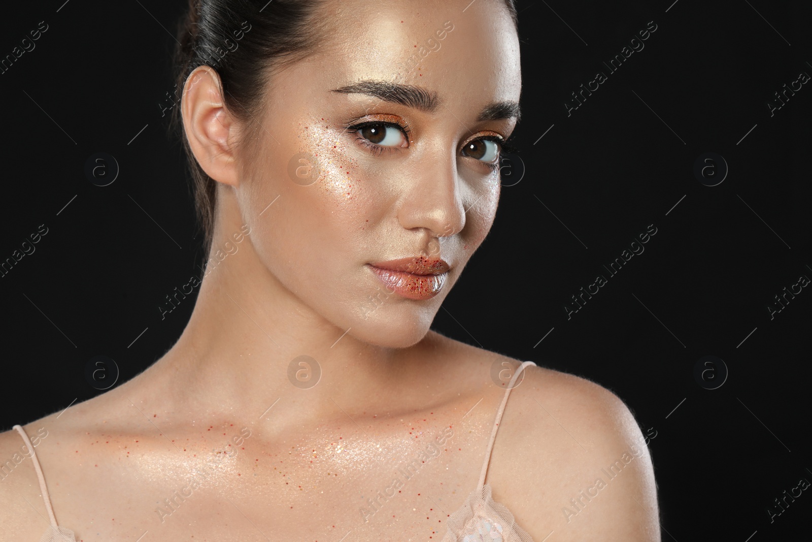 Photo of Beautiful young woman with glitter makeup on black background