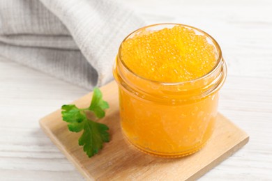 Photo of Fresh pike caviar in glass jar and parsley on white wooden table, closeup