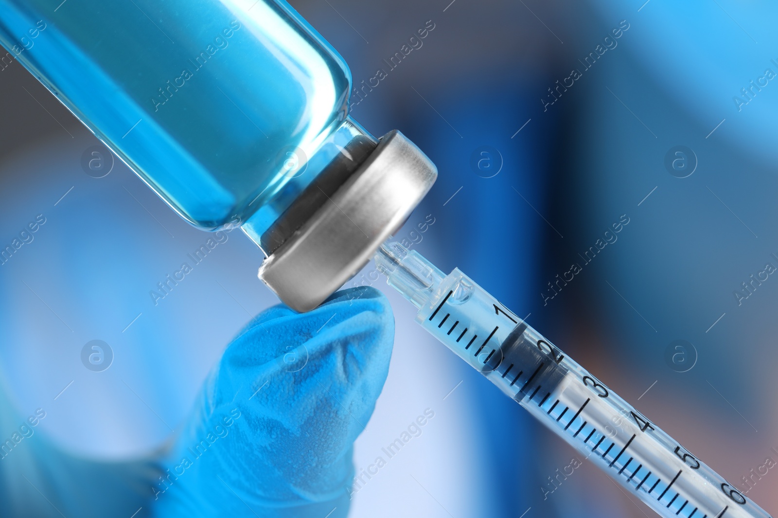 Photo of Doctor filling syringe with medication from glass vial, closeup