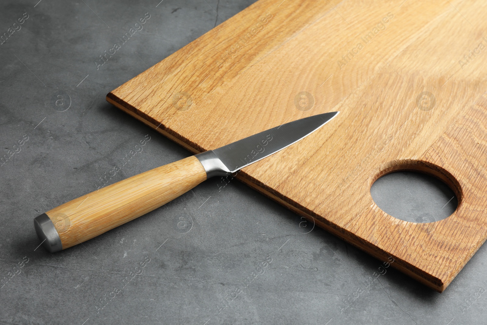 Photo of Knife and wooden board on grey textured table