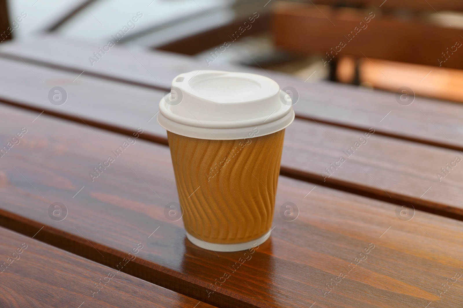 Photo of Takeaway paper cup with coffee on wooden table, closeup