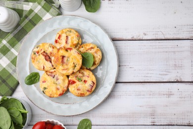 Photo of Delicious egg muffins with cheese and bacon on white wooden table, flat lay. Space for text