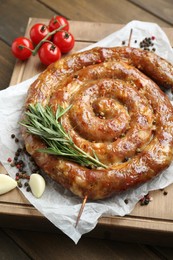 Photo of Delicious homemade sausages with spices and tomatoes on wooden table