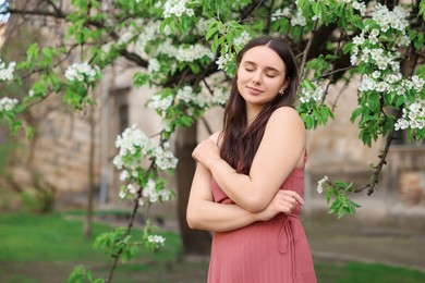 Beautiful woman near blossoming tree on spring day