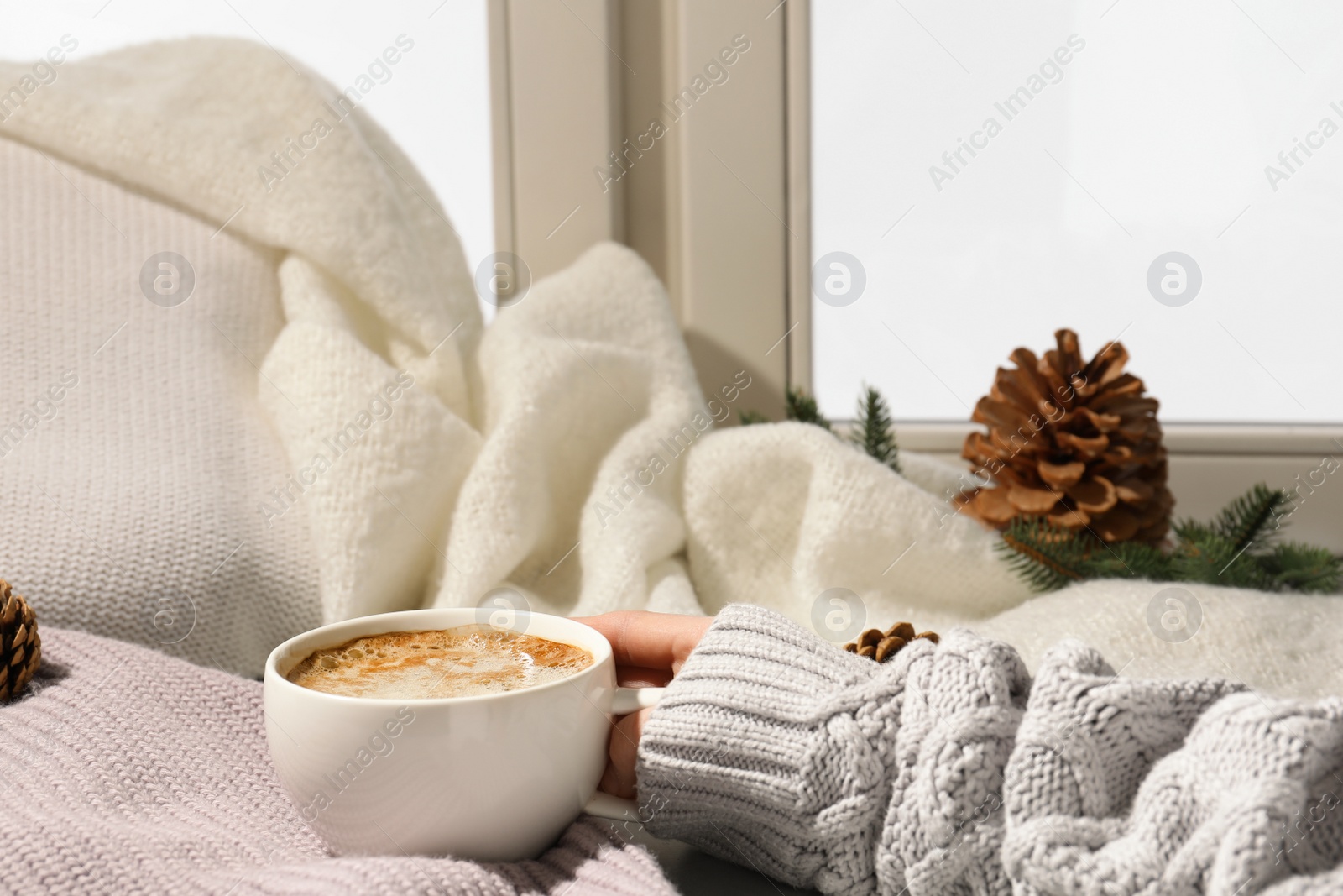 Photo of Woman with cup of coffee at window, closeup, space for text. Winter drink