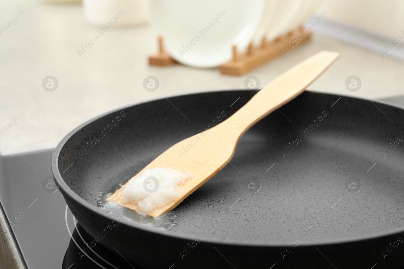 Photo of Frying pan with coconut oil on induction stove, closeup. Healthy cooking