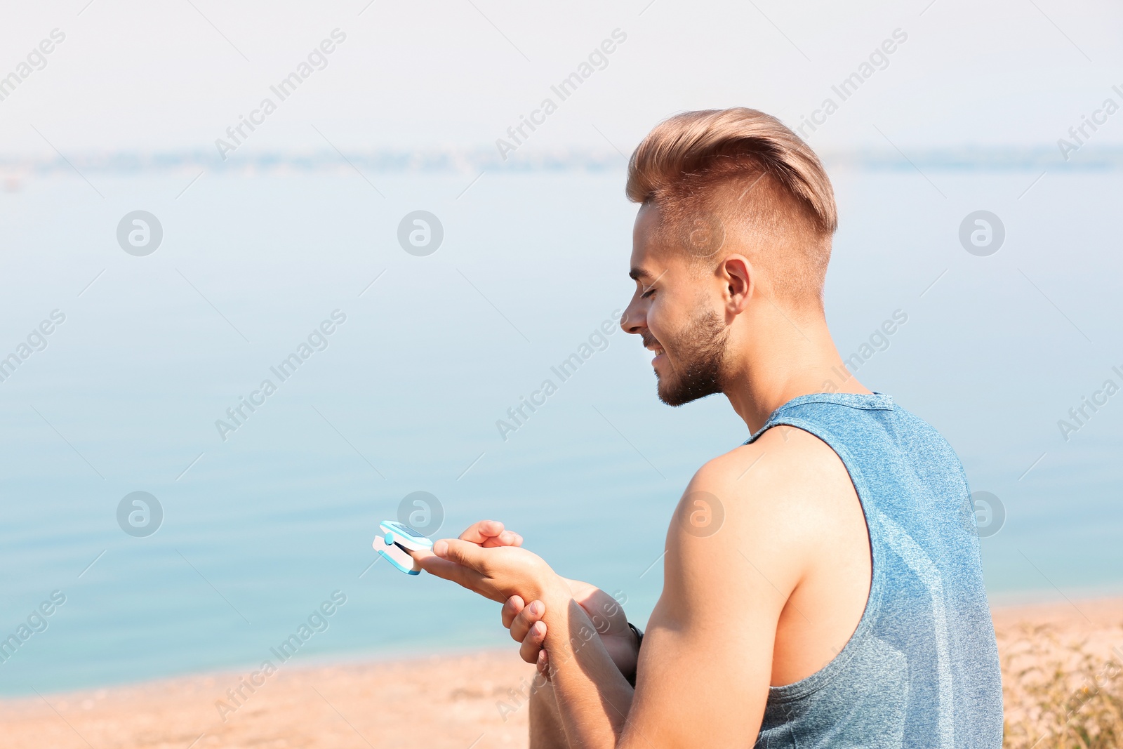 Photo of Young man checking pulse outdoors on sunny day