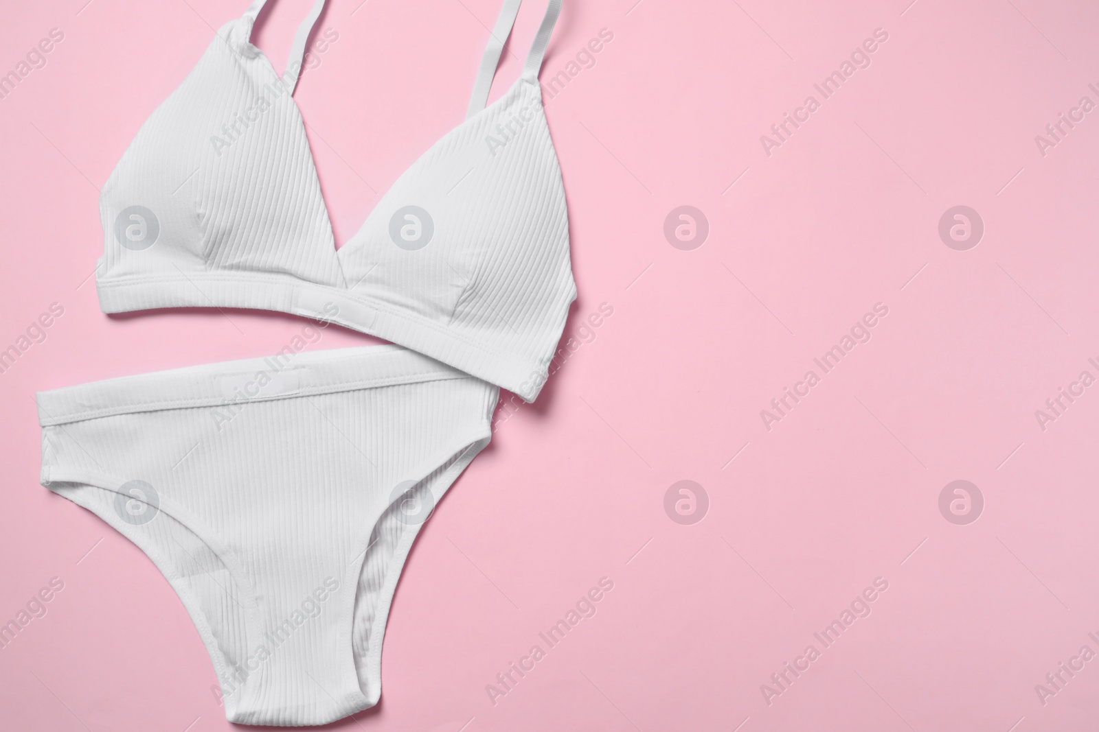 Photo of Stylish white women's underwear on pink background, flat lay. Space for text