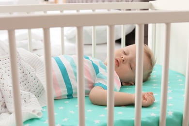 Cute little child sleeping in crib at home