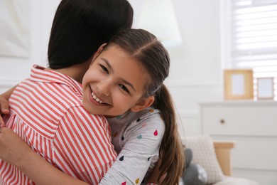 Photo of Cute little girl hugging her mother in living room. Adoption concept