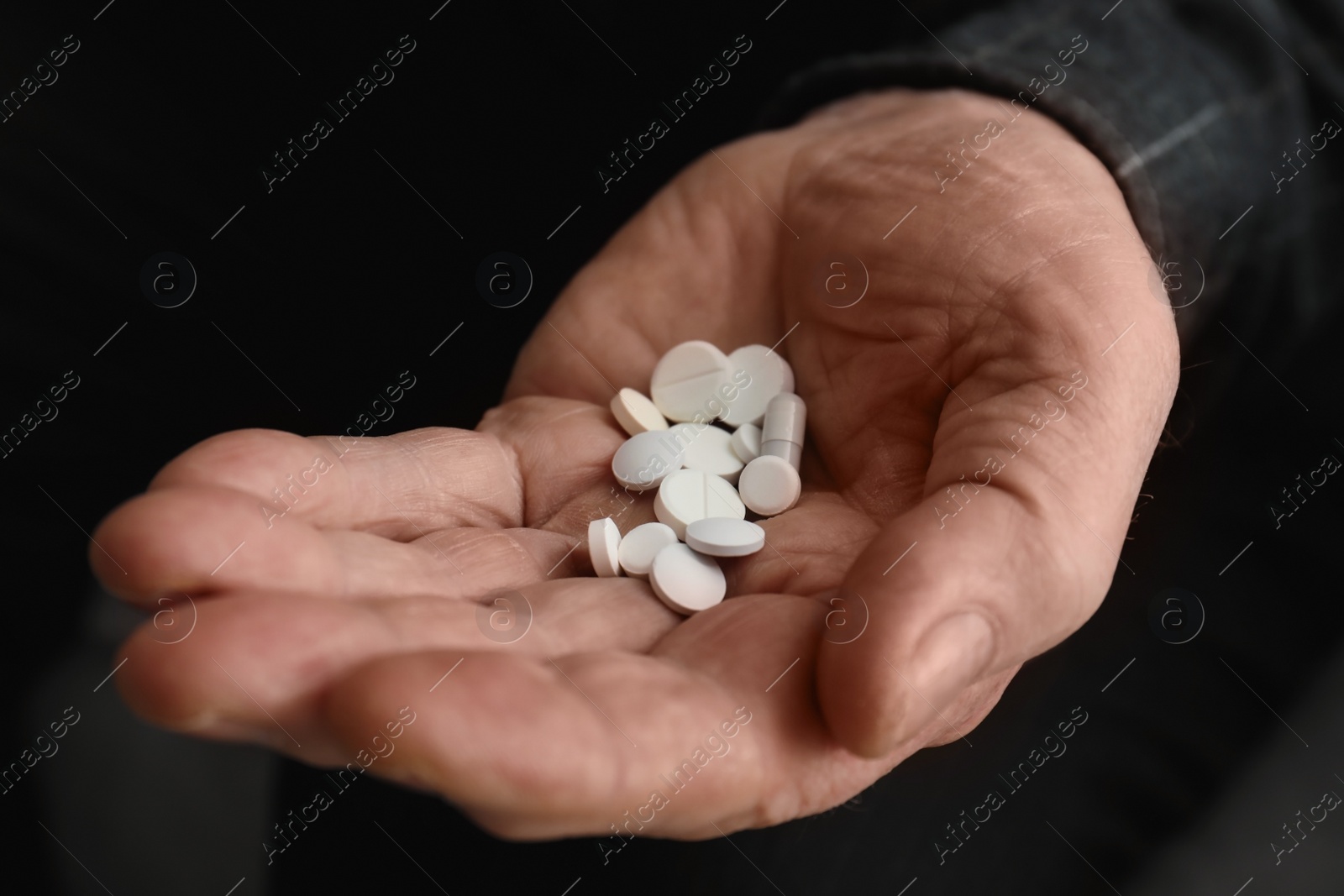 Photo of Senior man holding pills in his hand, closeup