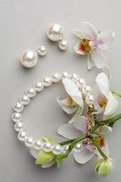 Photo of Elegant pearl earrings, bracelet and orchid flowers on white background, flat lay