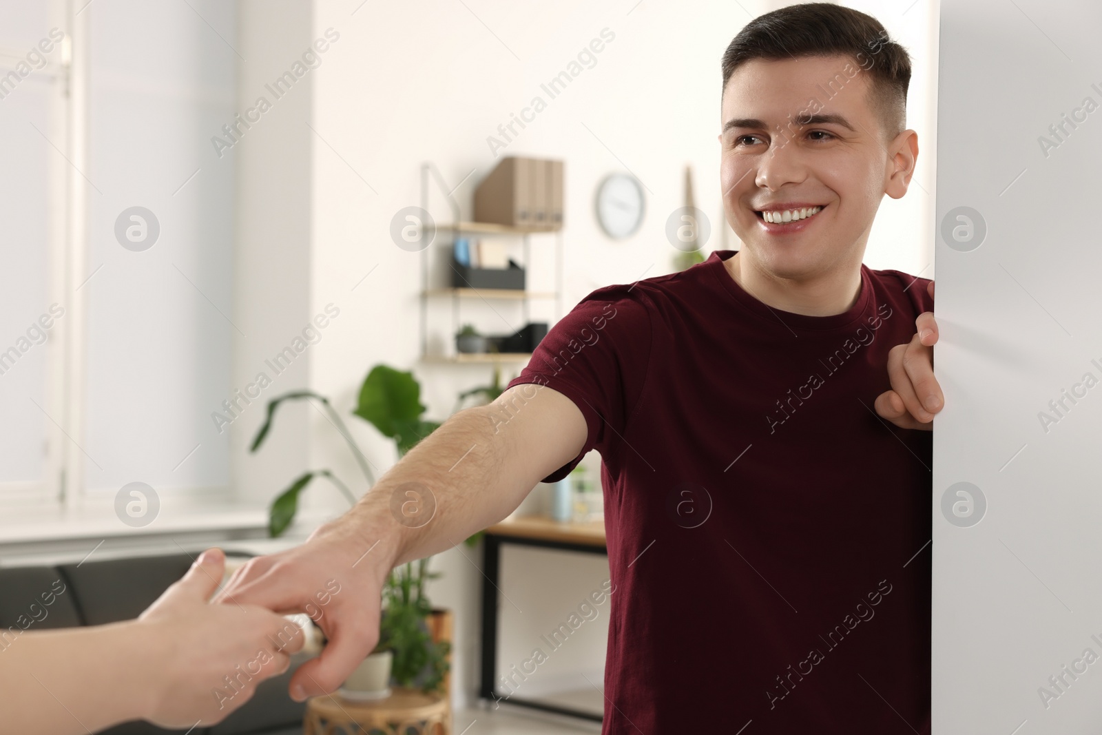 Photo of Handsome man inviting girlfriend to come in room at home