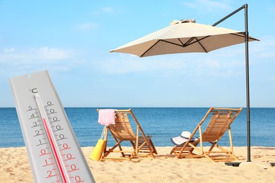 Weather thermometer and beautiful sandy beach with wooden sunbeds on background. Heat stroke warning