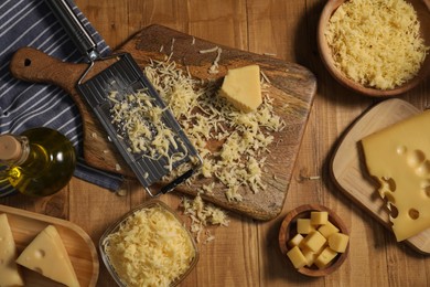 Different types of cheese and grater on wooden table, flat lay