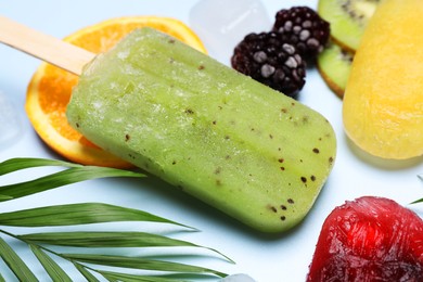 Photo of Delicious ice popsicles, fresh fruits and leaf on light background, closeup