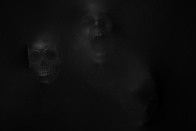 Photo of Silhouette of creepy ghost with skull behind black cloth