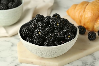 Photo of Bowl of fresh ripe blackberries on white marble table, closeup