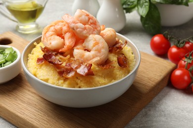 Photo of Fresh tasty shrimps, bacon and grits in bowl on table, closeup