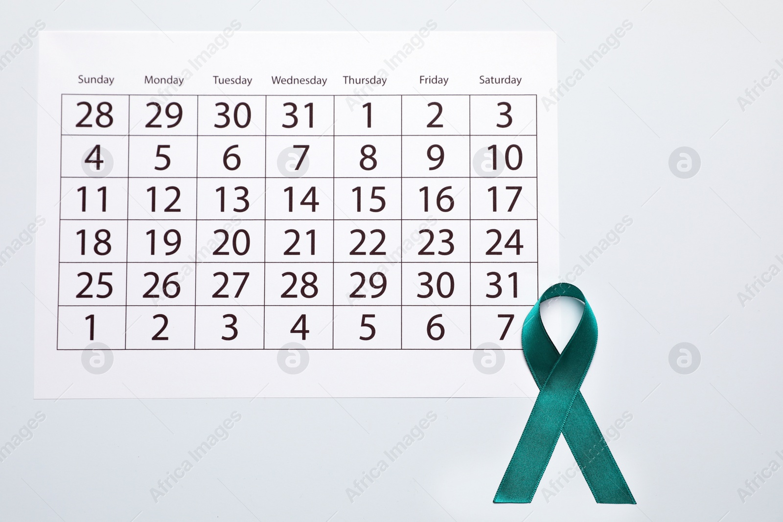 Photo of Teal awareness ribbon and calendar on white background, top view. Symbol of social and medical issues