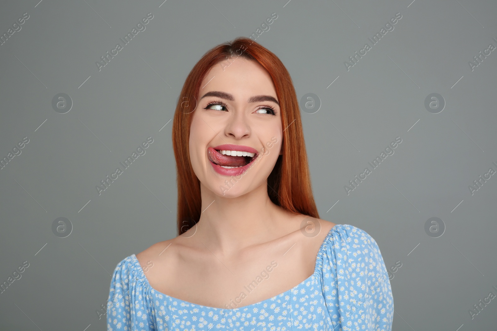 Photo of Happy woman showing her tongue on gray background