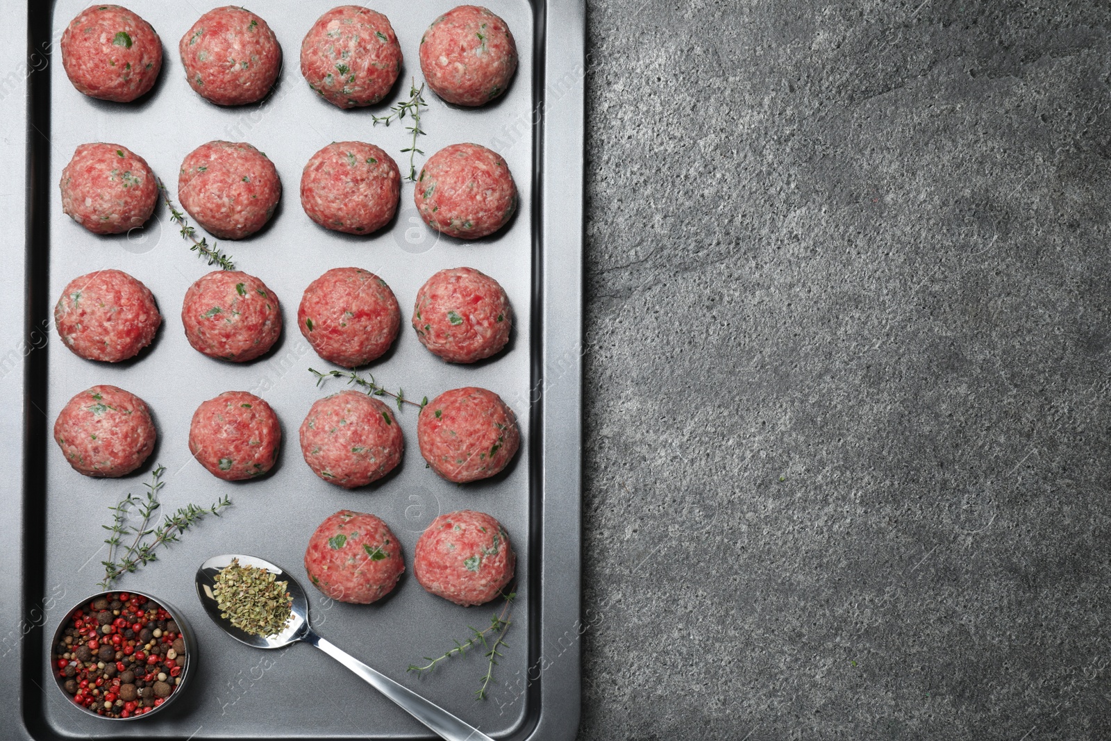 Photo of Many fresh raw meatballs on grey table, top view. Space for text