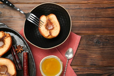 Tasty baked quinces served with honey on wooden table, flat lay. Space for text