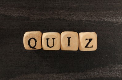 Photo of Cubes with word Quiz on wooden table, flat lay