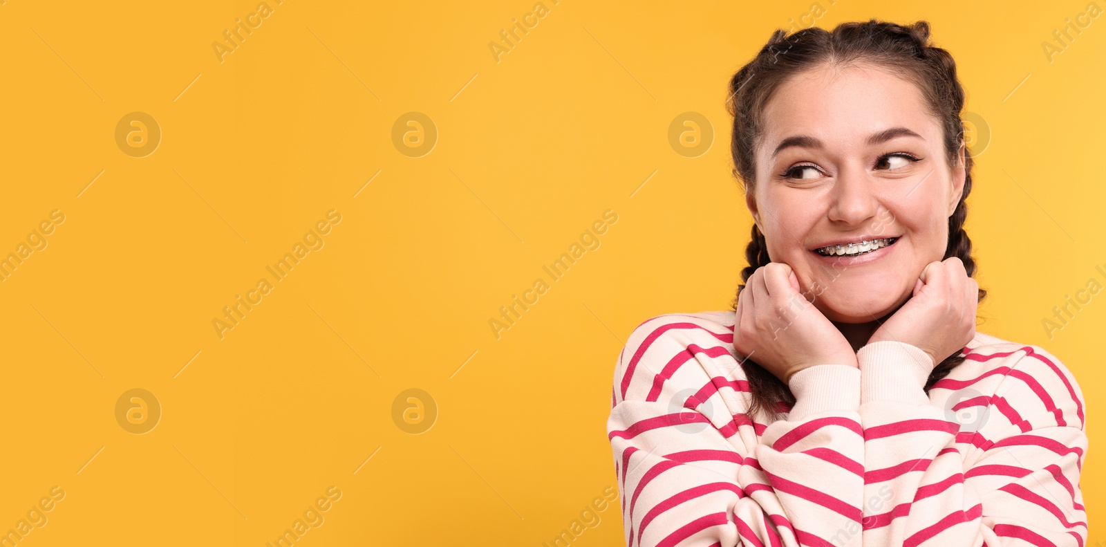 Image of Smiling woman with braces on orange background. Banner design with space for text