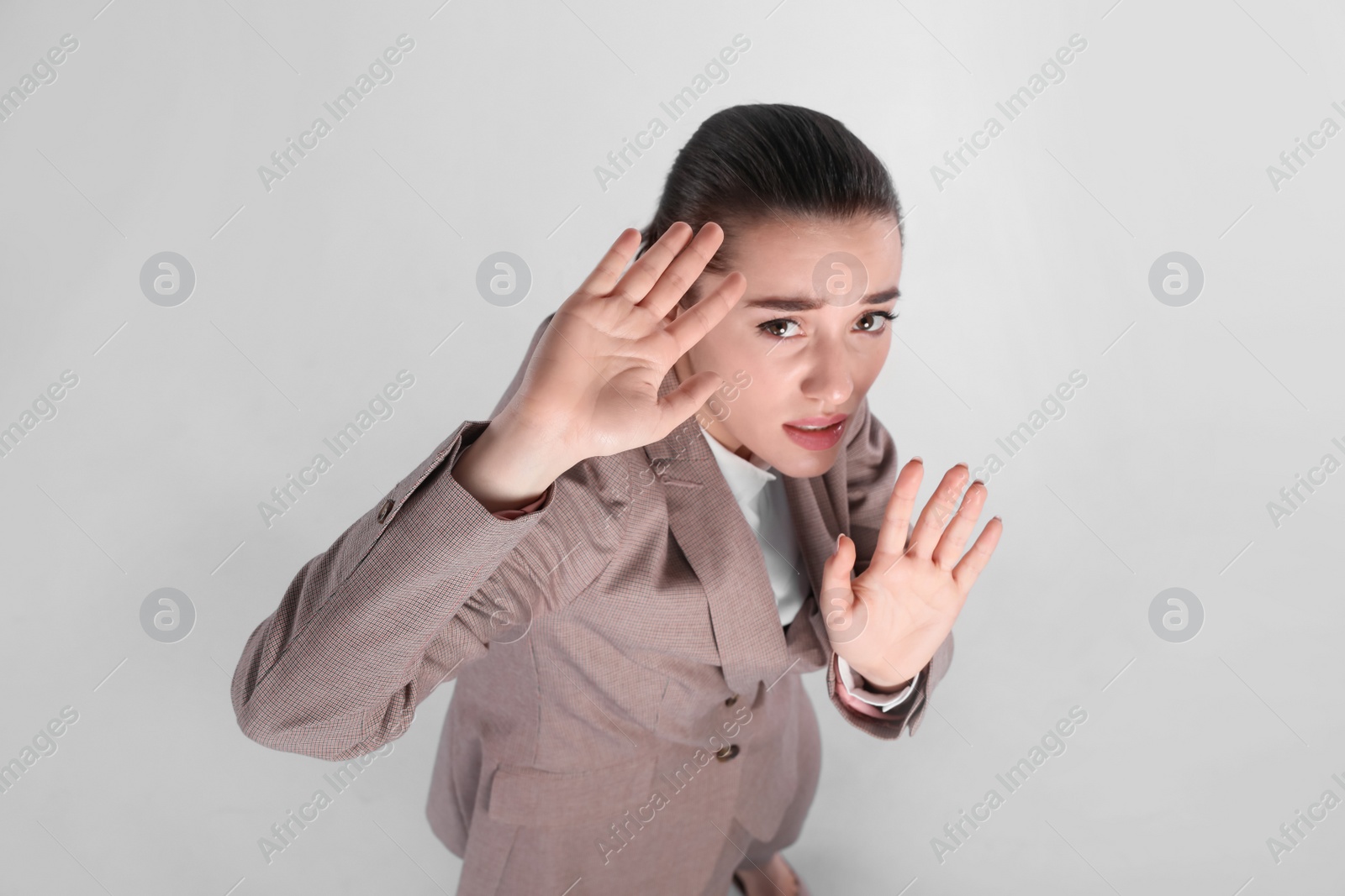 Photo of Young woman in suit evading something on light grey background, above view