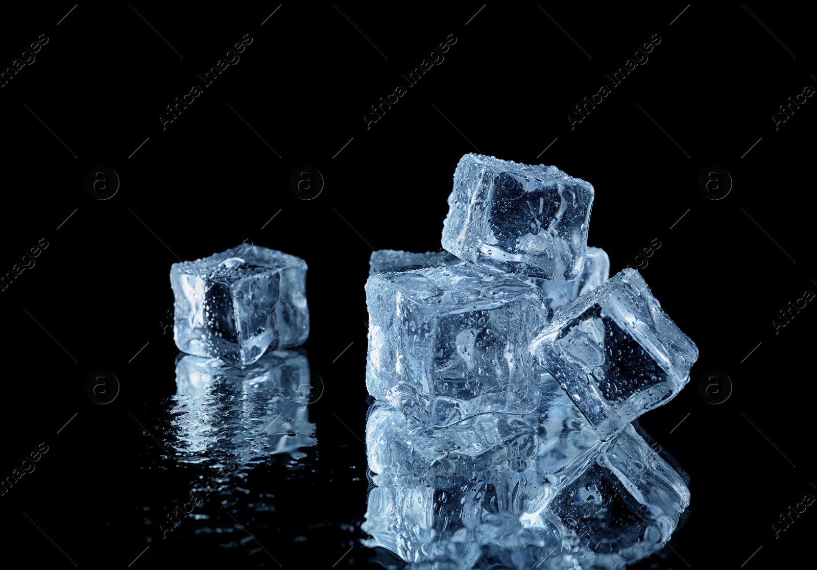 Photo of Transparent ice cubes on black mirror surface