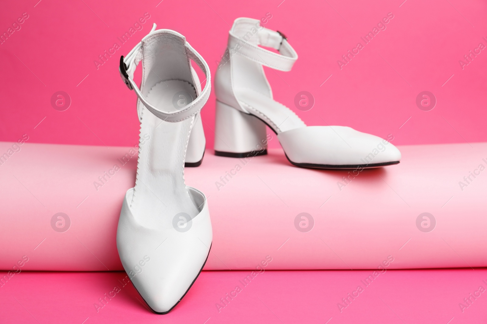 Photo of Stylish white female shoes on pink background