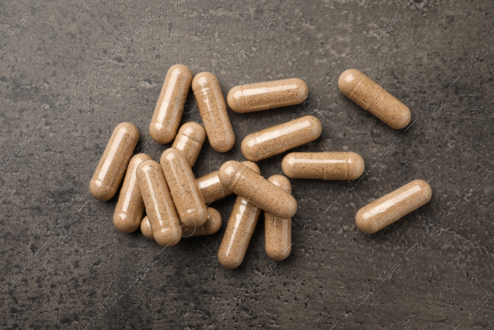 Photo of Dietary supplement capsules on grey table, flat lay