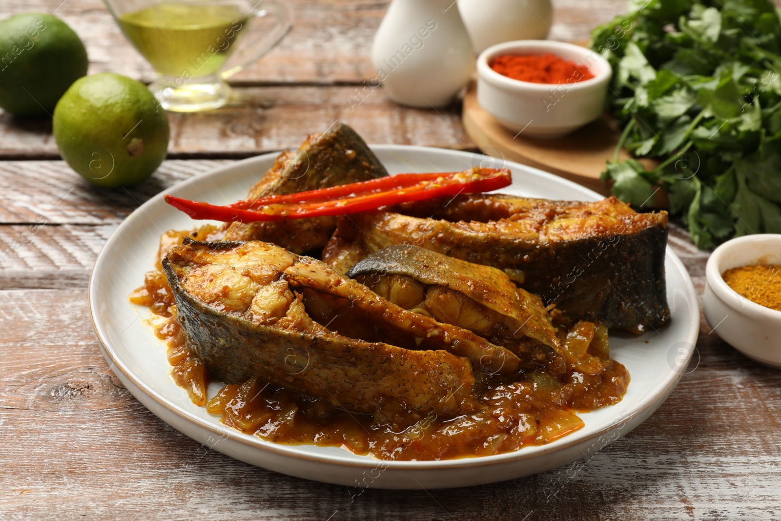 Photo of Tasty Indian fish curry on wooden table, closeup