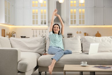 Photo of Young woman with laptop on sofa at home